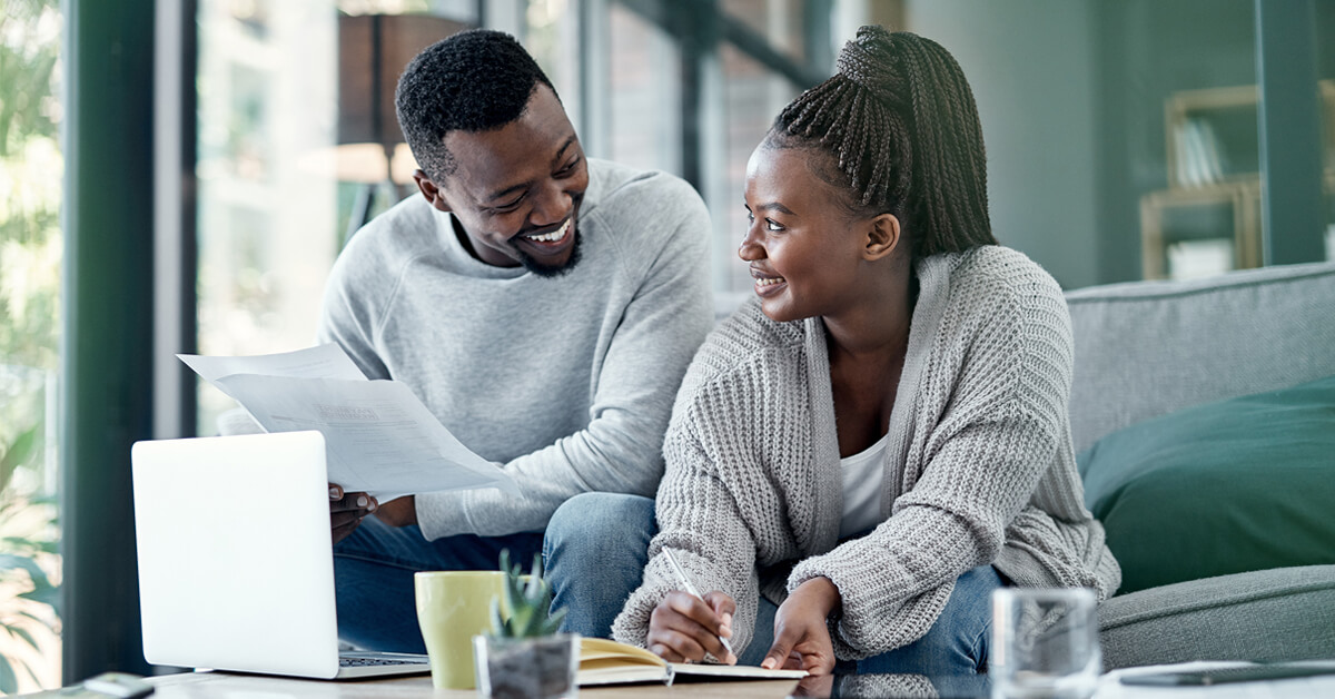 two people sitting on couch reviewing financial paperwork